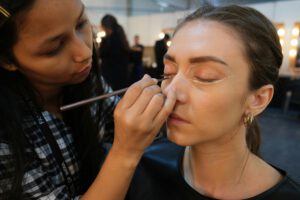 A makeup artist skillfully applies eye makeup to a model during a professional photoshoot.