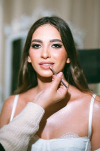 Close-up of a model getting lipstick applied by a professional makeup artist.