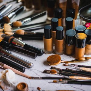 A variety of makeup brushes and foundation bottles arranged on a marble surface, showcasing beauty essentials.
